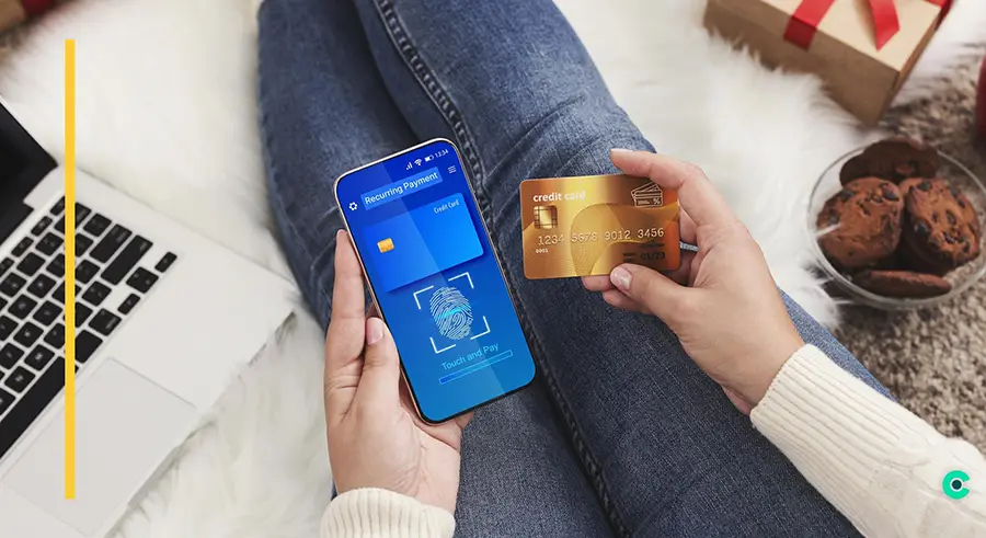 A person holding a credit card and a smartphone displaying a payment app.